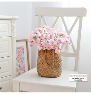 Pink silk camellia flowers in a woven straw basket on a white chair in home decor