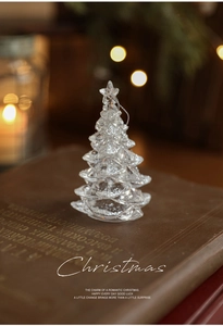 Glittery acrylic Christmas tree ornament with silver sequins on a vintage book