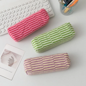 Detailed knit texture of colorful striped checkered makeup bags on a white desk