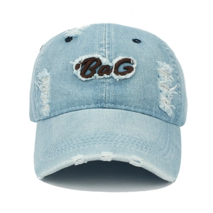 Detailansicht der BaG-Stickerei und der Distressed-Löcher auf der gewaschenen Denim-Kappe