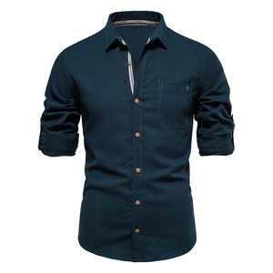 Detail of dark green cotton shirt with brown buttons and rolled sleeves on ghost mannequin