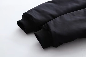 Detailaufnahme der schwarzen Bomberjacke mit gerippten Ärmelbündchen und winddichtem Stoff