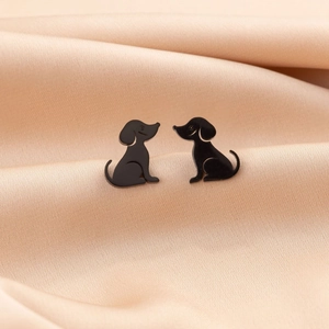 Macro detail of cute black stainless steel dog-shaped stud earrings on silk fabric