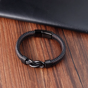 Detail of a braided leather bracelet with infinity metal knot and magnetic clasp on wood