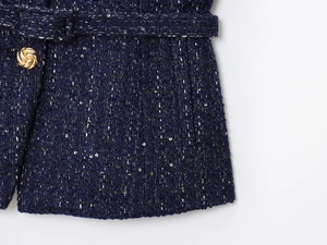 Dettaglio giacca in tweed blu scuro con paillettes dorate e bottone dorato a rilievo