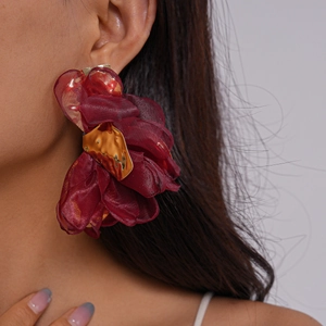 Gros plan d'un mannequin portant de grandes boucles d'oreilles fleurs en mousseline rouge