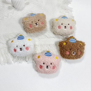 Close-up of colorful plush bear brooches in brown, beige, white, and pink fleece
