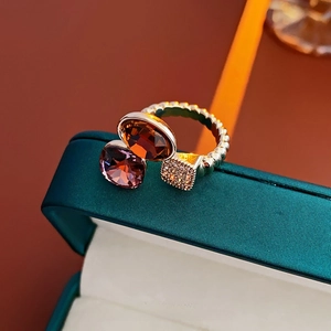 Détail d'une bague argentée avec ambre et rubis posée sur un coffret en cuir vert foncé