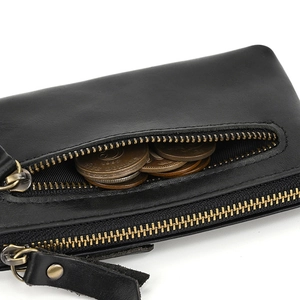 Detail of a black leather coin purse featuring a brass metal zipper and leather puller
