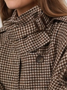 Macro detail of houndstooth wool coat featuring stand collar and brown button texture