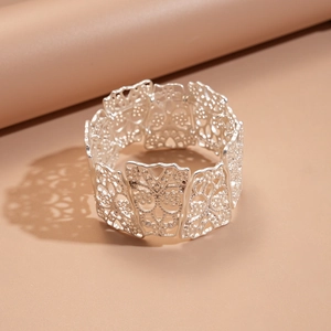 Close-up of matte silver hollow floral pattern on a wide lace-style bangle