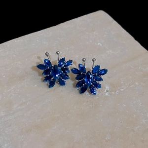 Detailed macro view of dark blue butterfly earrings with crystals on marble stone