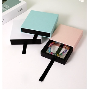 Detail view of drawer-style jewelry gift boxes with ribbon handles in assorted pastel colors