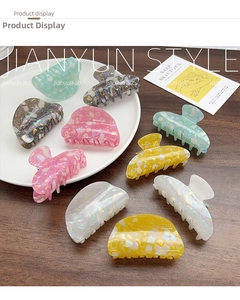 Detail showing colorful marble texture acetate hair claws arranged on a wooden table