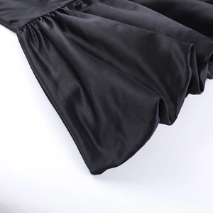 Detailed close-up of glossy black satin fabric with elegant pleated textures and drape