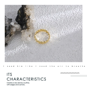 Detailed view of a gold scalloped edge ring on a textured stone background for women