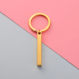Close-up of a minimalist golden stainless steel rectangular bar pendant on a keychain