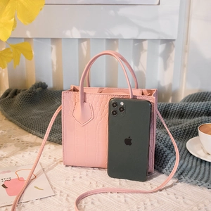 Pink crocodile pattern mini square crossbody bag with handle on elegant lace background