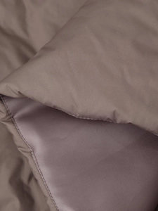 Detailed close-up of quilted coffee brown padded jacket fabric texture and neat stitching