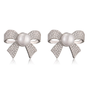 Close-up of silver bow stud earrings with sparkling cubic zirconia and a center pearl
