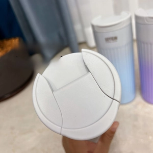 Detail showing the portable flip-top lid design of the white stainless steel coffee mug