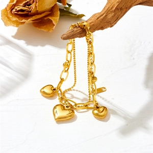 Elegant gold double-layer heart charm bracelet featuring bead and link chain design