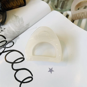 Detail of a creamy translucent resin D-shaped hair claw clip on a white magazine background