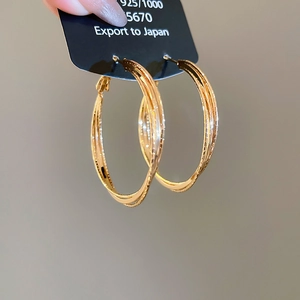 Macro detail of 18k gold plated triple layer interwoven hoop earrings on display card