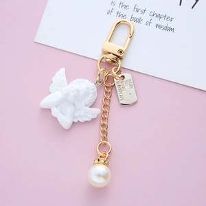 Detailed view of Baroque angel keychain with white resin cupid, pearl heart and golden clip