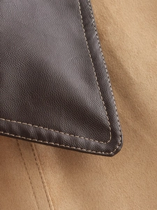Close-up of contrast stitching on dark brown leather and camel suede jacket pocket