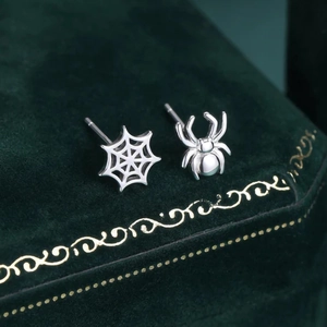Detalle de pendientes de araña y telaraña plateados sobre un joyero de terciopelo verde