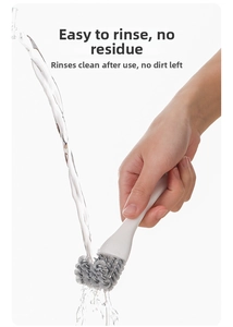 Detail showing hand holding ergonomic brush with spiral bristles under running water for cleaning