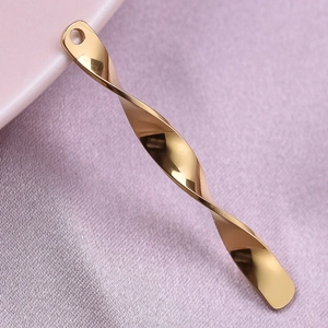 Detailed view of a golden spiral twist pendant on purple silk fabric for jewelry making
