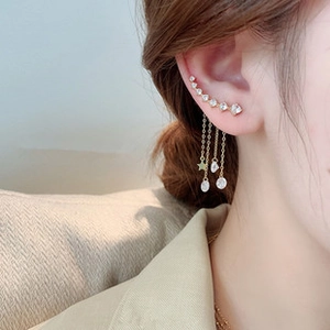 Close-up of golden tassel earrings with crystal stars and pearls on a female model