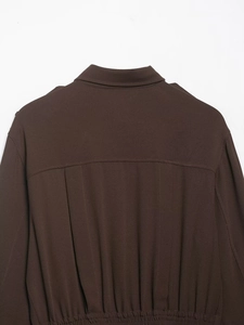 Detailed view of dark brown twill fabric texture on shirt back shoulder and collar seam