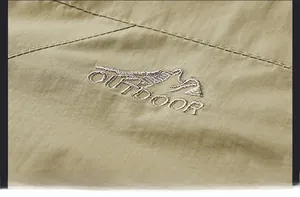 Detail der khakifarbenen Outdoor-Jacke mit hochwertiger Bergstickerei und windfestem Stoff