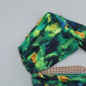 Detail of green and blue abstract print dress with decorative gold metal chain and draping