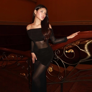 Close-up of elegant black off-shoulder dress with mesh sleeves and corset-style lace panels