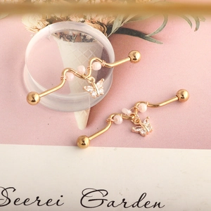 Detail view of golden curved barbell earrings with pink beads and crystal butterfly charm
