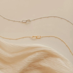 Macro shot of minimalist gold and silver interlocking ring pendant necklaces with beads