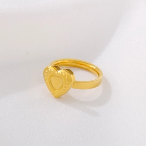 Minimalist gold stainless steel ring with heart pattern on white textured background