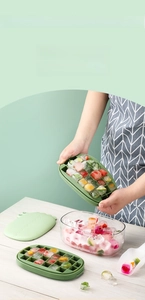 Flexible silicone ice tray showing hands twisting it to release fruit ice cubes into a box