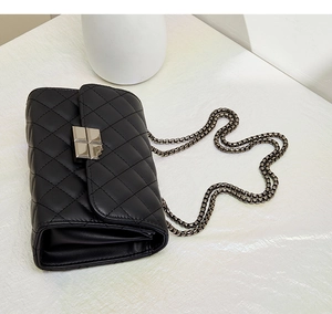 Close-up of black quilted leather shoulder bag featuring silver metal lock and chain