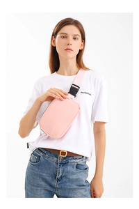 Detail of pink nylon chest bag featuring adjustable strap and large black plastic buckle