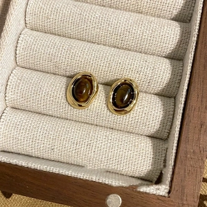 Close-up of Maillard tiger eye stone geometric earrings in a wooden jewelry box