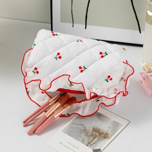Détail d'une trousse à maquillage matelassée avec broderie cerise et bords à volants