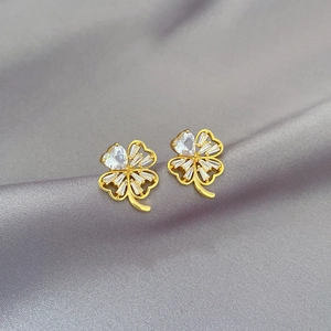 Luxurious four-leaf clover stud earrings with white zircons on grey silk background