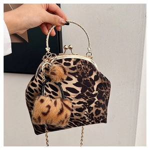 Detail of leopard print shell bag with gold metal handle and fuzzy charm accessory