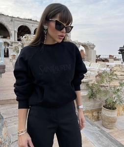 Detail view of the black crewneck sweatshirt with embroidered brand logo and kangaroo pocket
