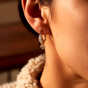 Gros plan d'une boucle d'oreille fleur en or avec zircons portée par un mannequin